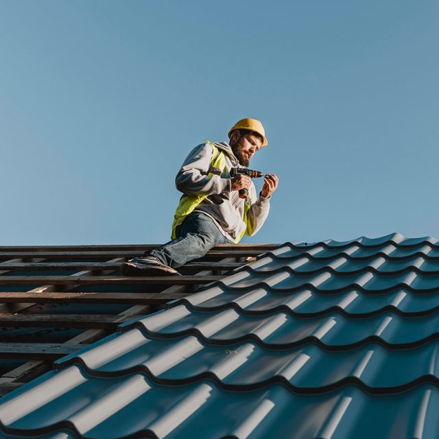 Ein Arbeiter sitzt auf einem Dach, um eine Reparatur vorzunehmen